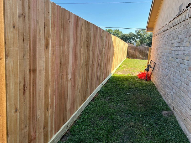 Newly installed cedar privacy fence along a brick home in Conroe, TX